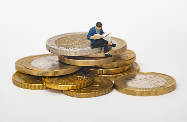 Figura em miniatura sobre moedas representando poupança